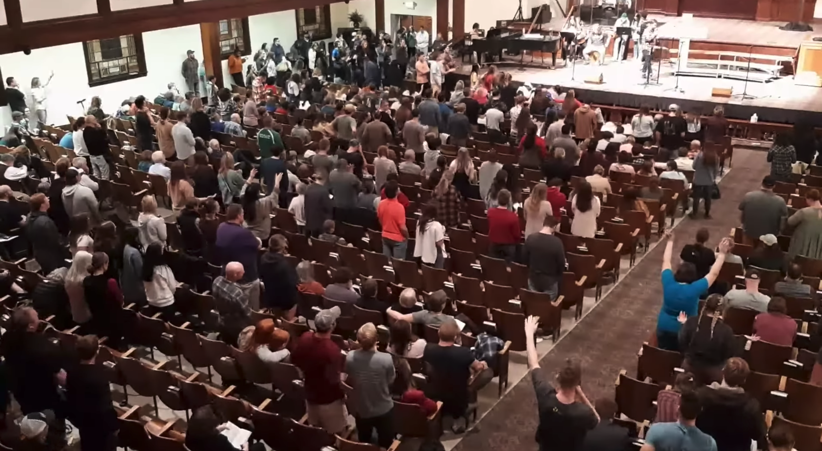 學生在禮堂中敬拜、禱告。（圖／截圖自YouTube @OfOneAccord）